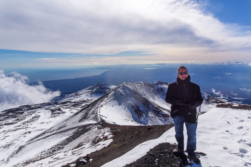 JR on top of Mount Etna with Catania and the Mediterranean Sea behind him
