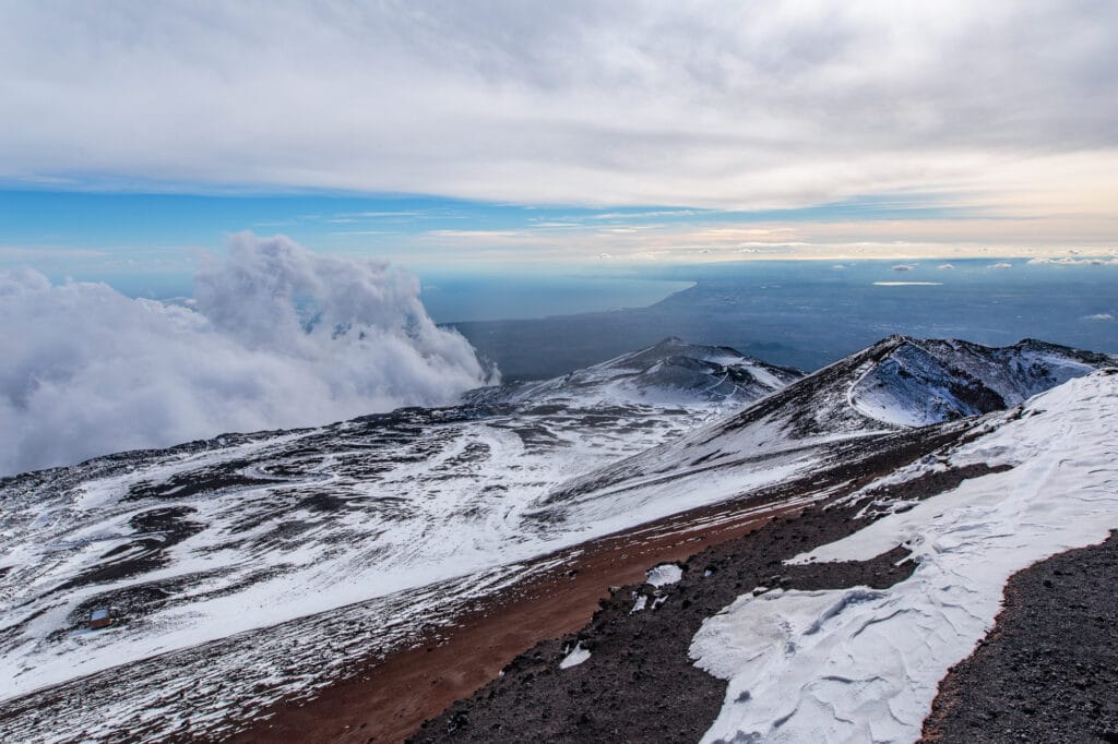Standing atop a volcano rim on Mount Etna in Sicily, Italy