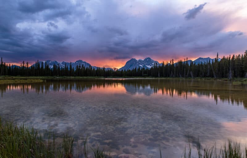The sun sets over a pond in Spray Valley Provincal Park in Alberta, Canada.