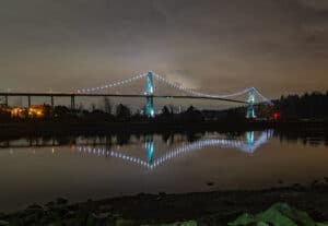 A night time photo of Lions Gate Bridge from the banks of the Capilano river in British Columbia
