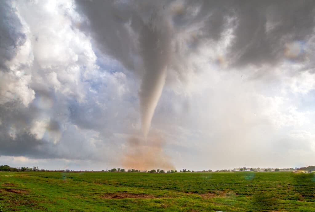 Glowing white tornado with a red dirt cloud around it's base near Lockett, Texas on April 23, 2021.